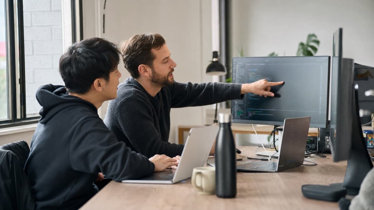Two software developers collaborating beside a computer monitor